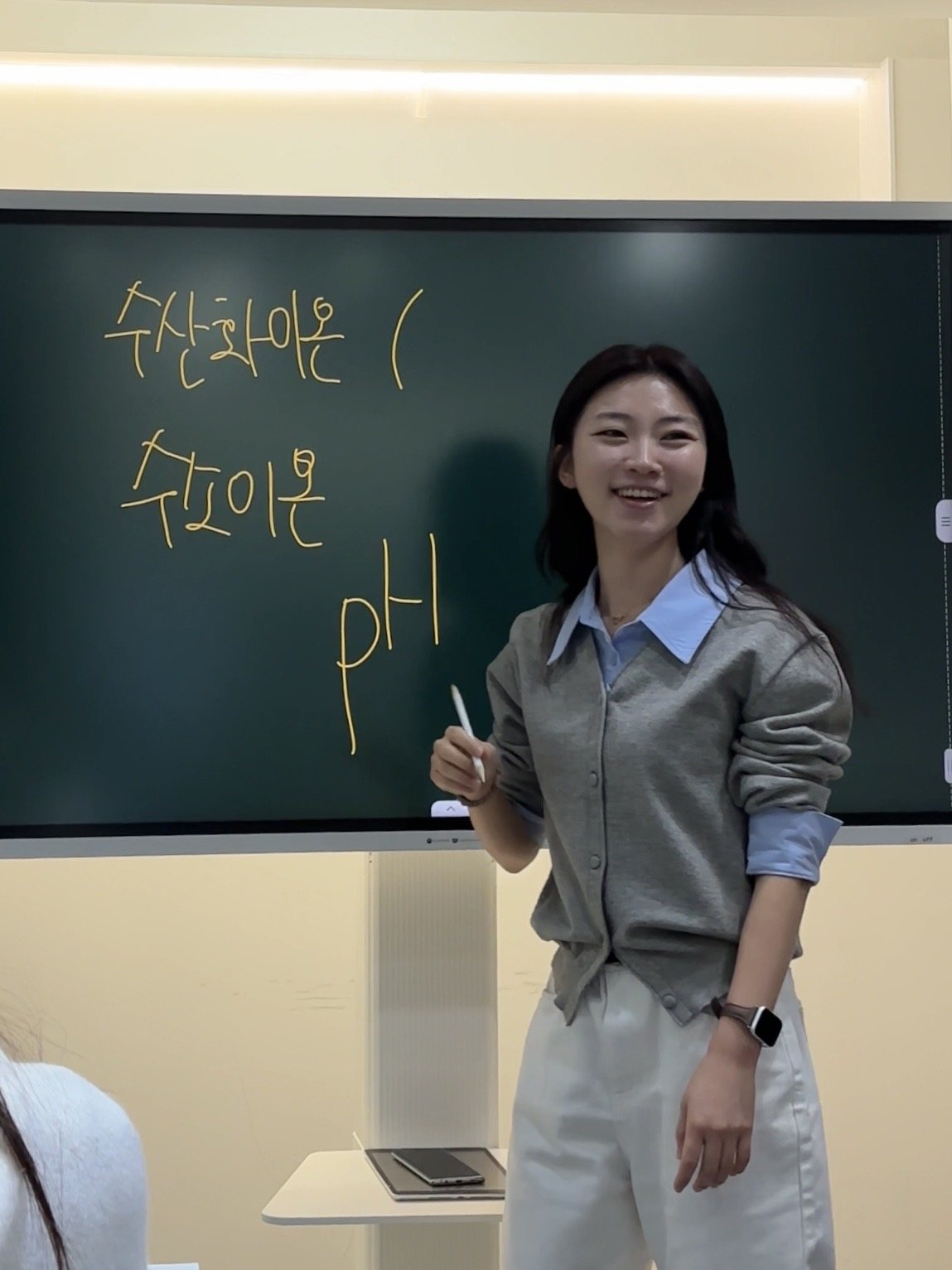 지아 원장이 화이트보드 앞에서 이론을 설명하는 수업 장면